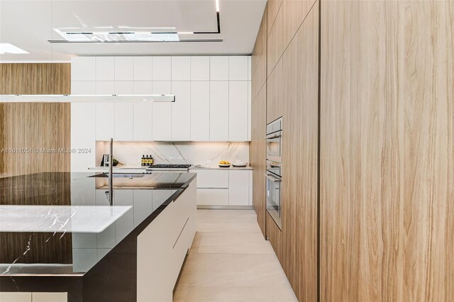 2832 Coconut Ave Unit 2832, Miami, FL 33133 - kitchen featuring stainless steel oven, light tile patterned floors, decorative backsplash, white cabinets, and modern cabinets