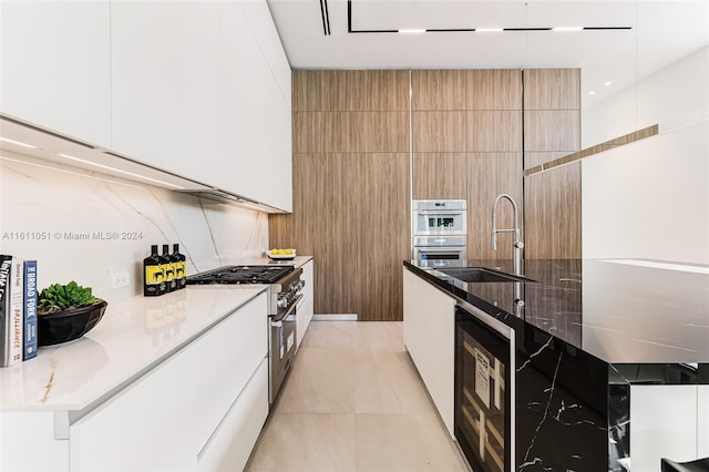 kitchen featuring light stone counters, wine cooler, sink, white cabinets, and stainless steel appliances