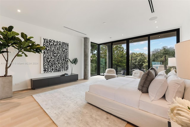 bedroom with a wall of windows and hardwood / wood-style floors