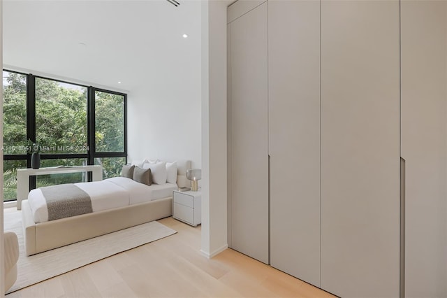 bedroom featuring a wall of windows and light hardwood / wood-style floors