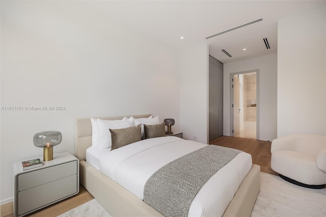 bedroom with light wood-type flooring and ensuite bathroom