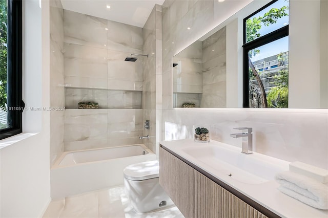 full bathroom with vanity, tiled shower / bath combo, toilet, and plenty of natural light