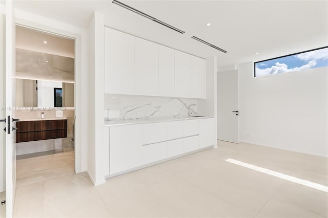 interior space featuring decorative backsplash and white cabinets