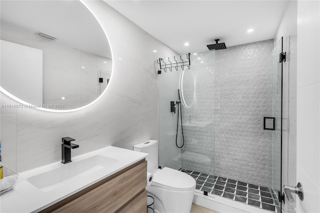 bathroom featuring vanity, toilet, a shower with shower door, and tile walls