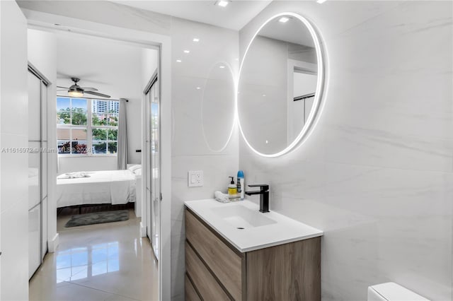 bathroom with vanity, ceiling fan, tile patterned flooring, and tile walls