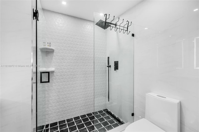 bathroom featuring a shower with door and toilet