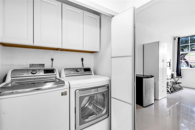 laundry room featuring light tile patterned flooring, cabinets, and washer and clothes dryer