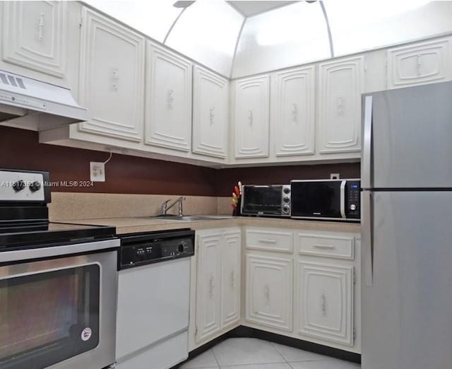 kitchen with appliances with stainless steel finishes, white cabinetry, light tile patterned flooring, and custom range hood