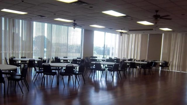 dining area with ceiling fan, a drop ceiling, and a wall of windows