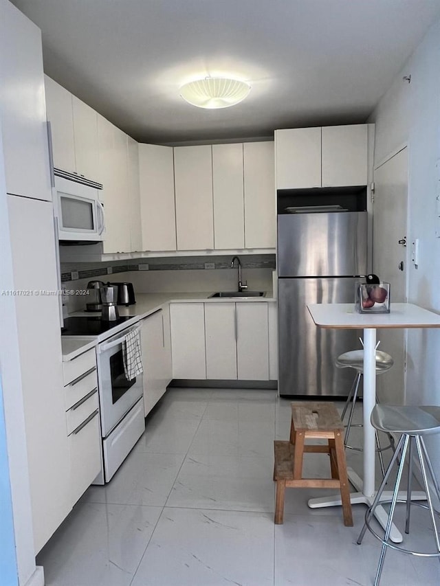 kitchen featuring white appliances, sink, and white cabinets