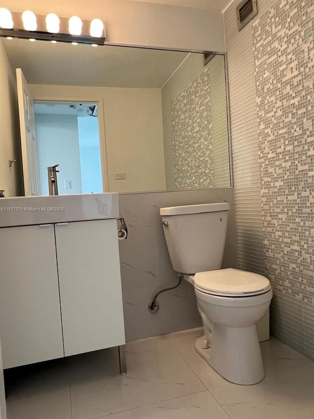 bathroom featuring tile walls, vanity, and toilet