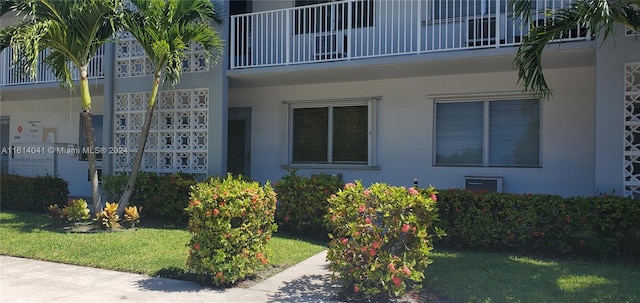 view of side of home with a balcony and a lawn