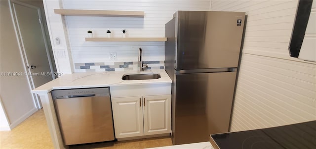 kitchen with sink, light stone counters, backsplash, and stainless steel appliances