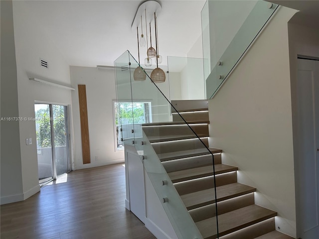 staircase featuring a towering ceiling and wood-type flooring