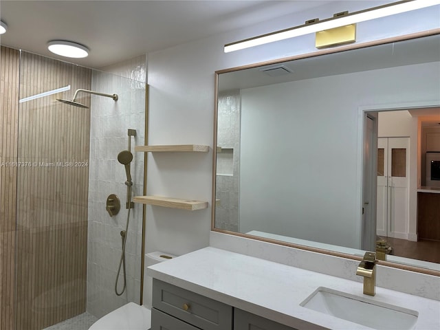 bathroom with tiled shower, vanity, and toilet