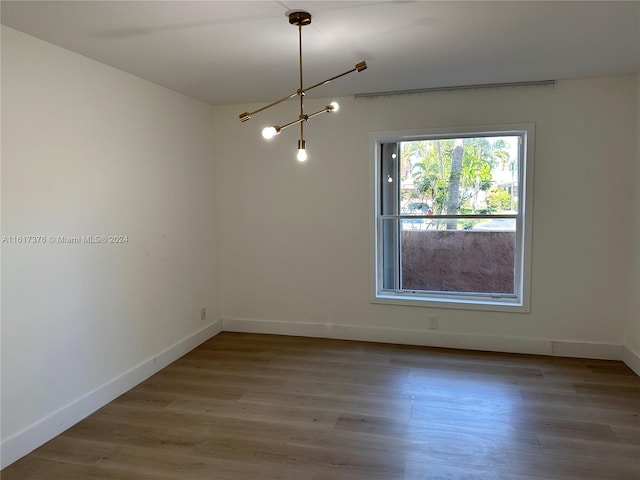 empty room featuring hardwood / wood-style flooring and a chandelier