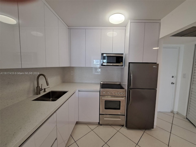 kitchen with white cabinetry, tasteful backsplash, stainless steel appliances, sink, and light tile patterned floors