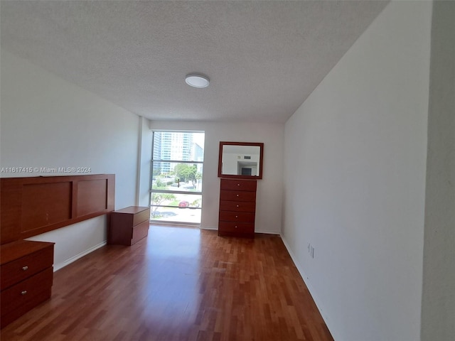 unfurnished bedroom with dark hardwood / wood-style flooring and a textured ceiling