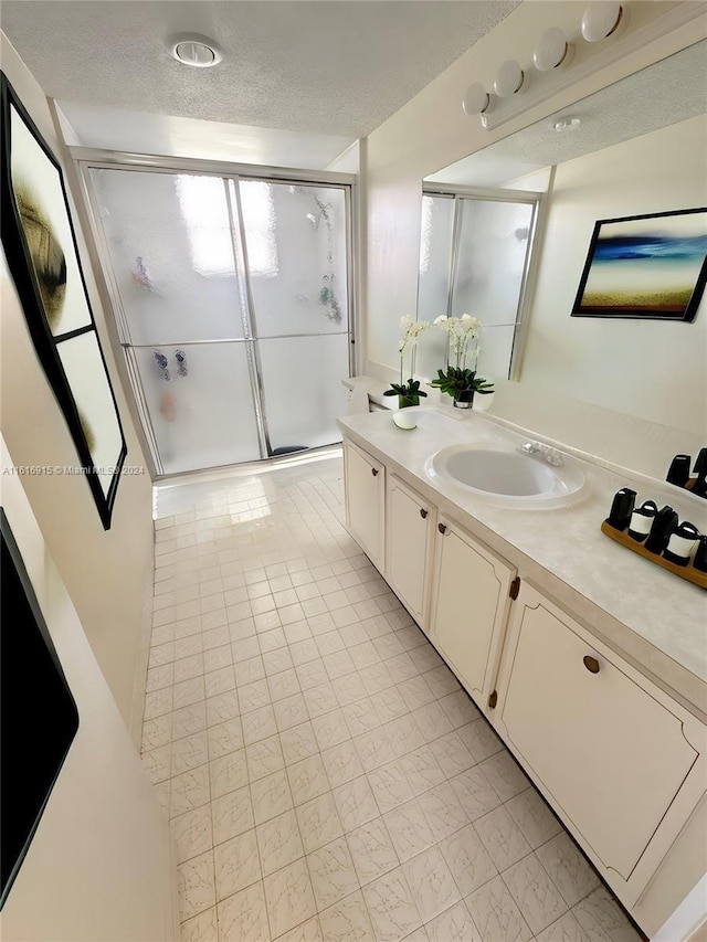 bathroom featuring a textured ceiling, vanity, and an enclosed shower