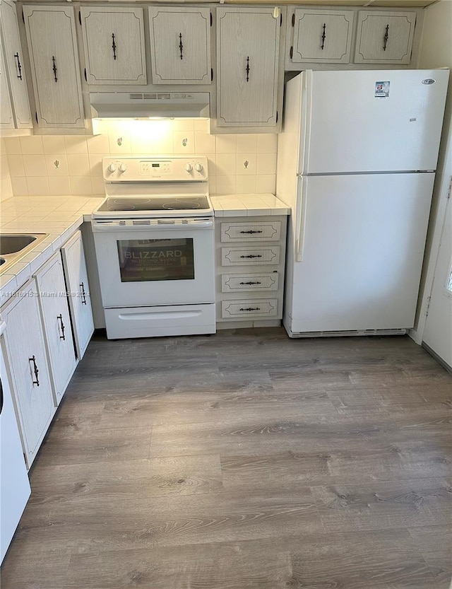 kitchen with light wood-type flooring, white appliances, and backsplash