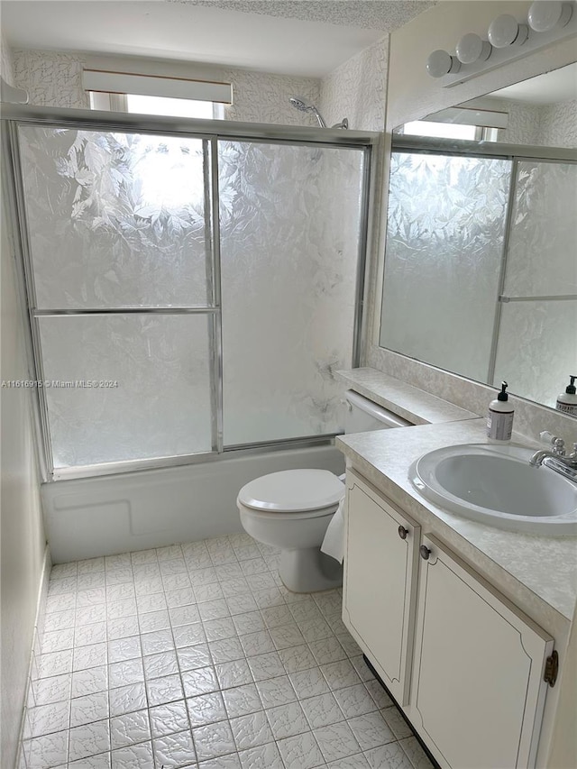 full bathroom with vanity, bath / shower combo with glass door, and toilet