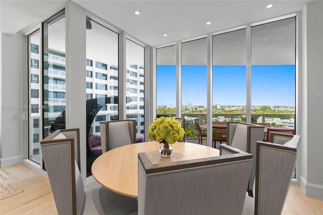 dining space with expansive windows, light hardwood / wood-style floors, and a healthy amount of sunlight