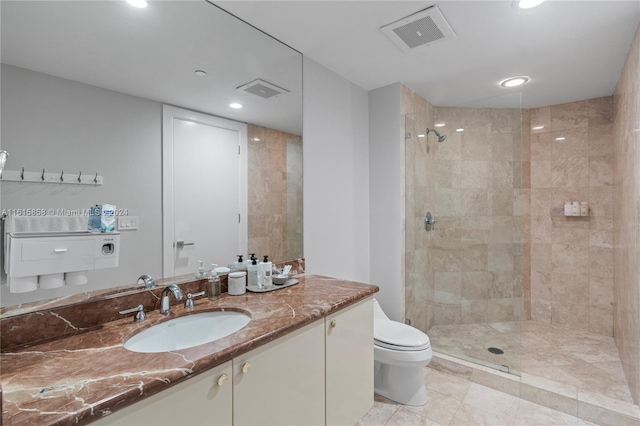 bathroom with a tile shower, tile patterned floors, vanity, and toilet