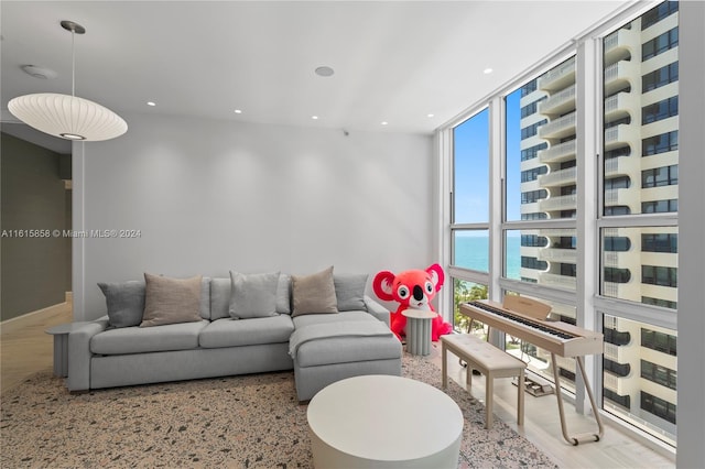 living room with a wall of windows, a water view, and light hardwood / wood-style flooring