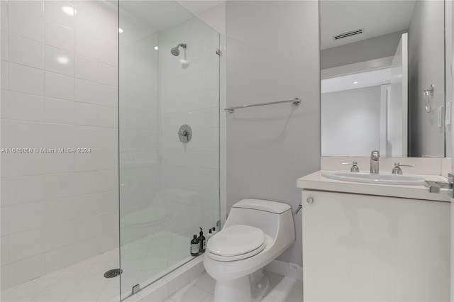 bathroom with a tile shower, vanity, toilet, and tile patterned floors