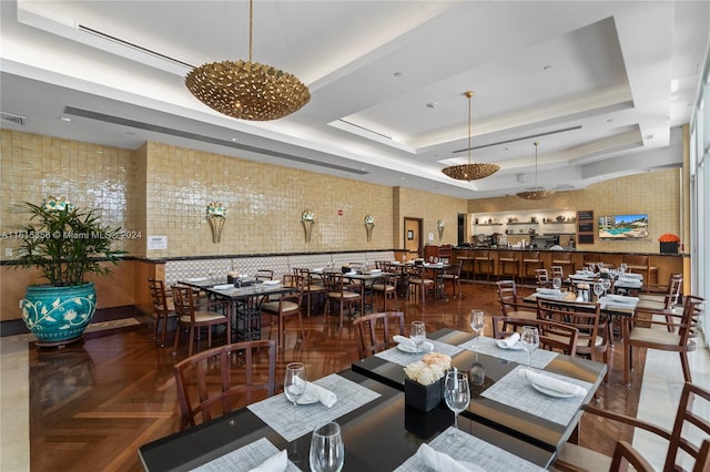 dining room with a raised ceiling, parquet floors, and a notable chandelier