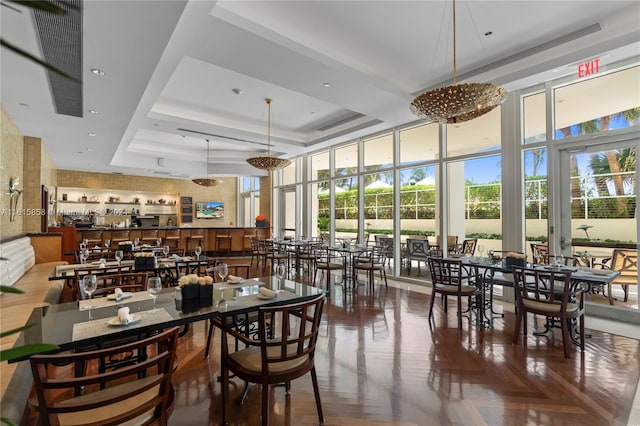 dining room featuring a notable chandelier, a raised ceiling, and parquet floors