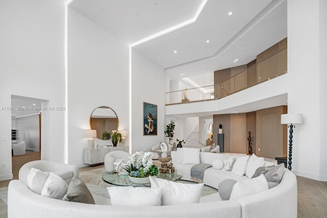 living room with light hardwood / wood-style floors and a towering ceiling