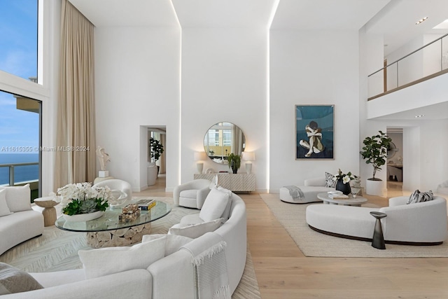 living room featuring light wood-type flooring, plenty of natural light, and a towering ceiling