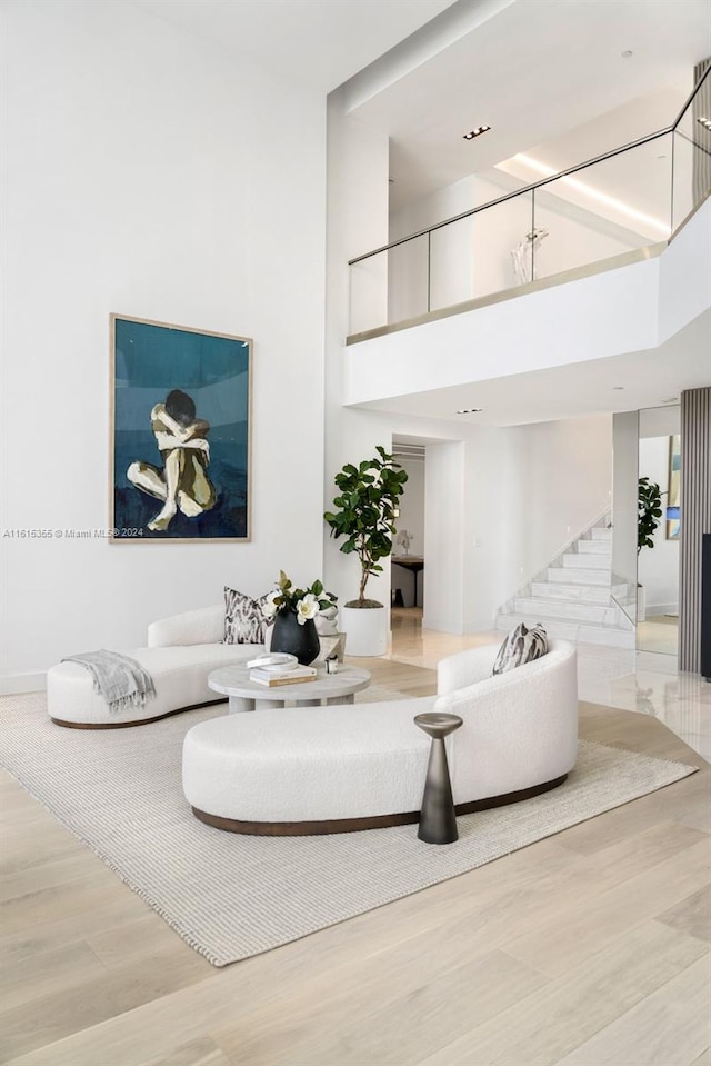 living room featuring light wood-type flooring and a high ceiling