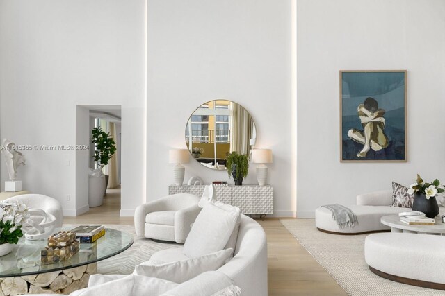 living room with light hardwood / wood-style floors and a towering ceiling