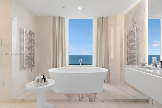 bathroom with tile patterned flooring, tile walls, radiator, and a water view