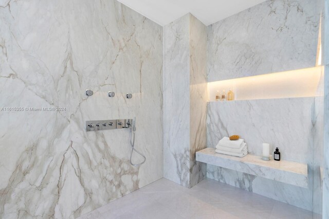 bathroom with tile walls, tile patterned floors, and a tile shower