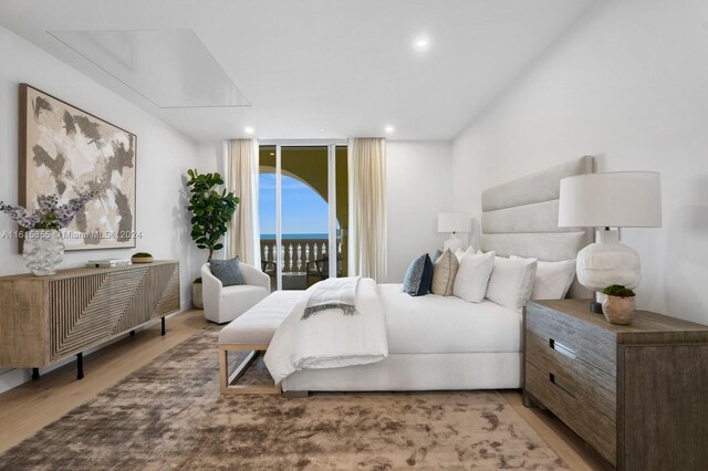 bedroom with access to outside, hardwood / wood-style floors, and expansive windows