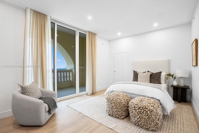 bedroom featuring access to outside, light hardwood / wood-style flooring, and a wall of windows