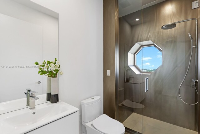 bathroom featuring a shower with door, toilet, and vanity