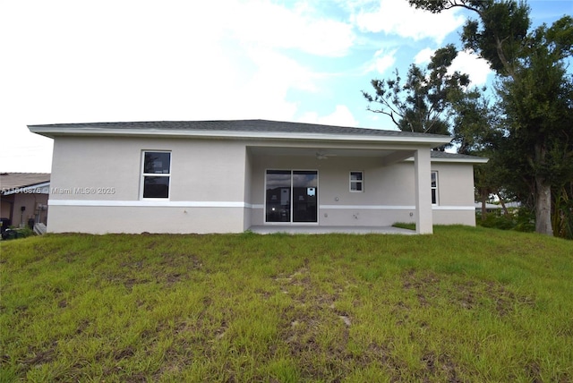 back of property featuring ceiling fan and a lawn