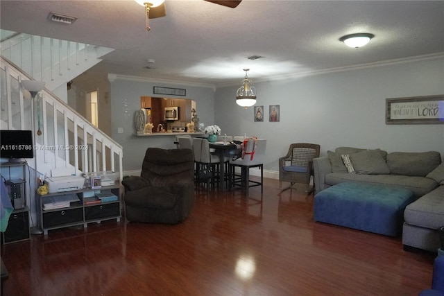 living room with ceiling fan, dark hardwood / wood-style flooring, ornamental molding, and a textured ceiling