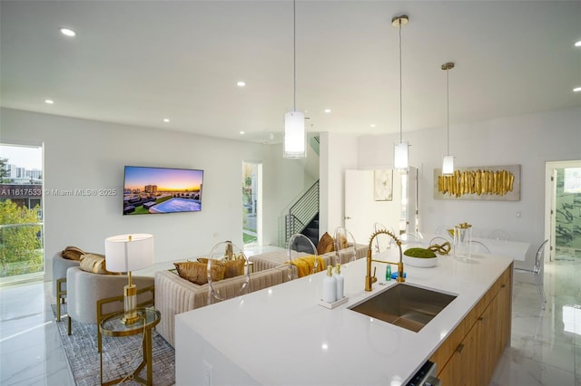 kitchen with pendant lighting, plenty of natural light, sink, and a kitchen island with sink