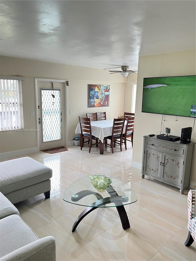 living room with light tile patterned flooring, ceiling fan, and baseboards