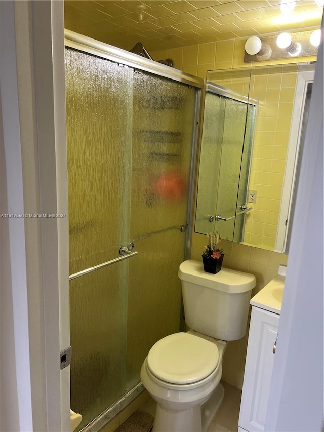 bathroom featuring tile patterned floors, a shower with shower door, toilet, and vanity