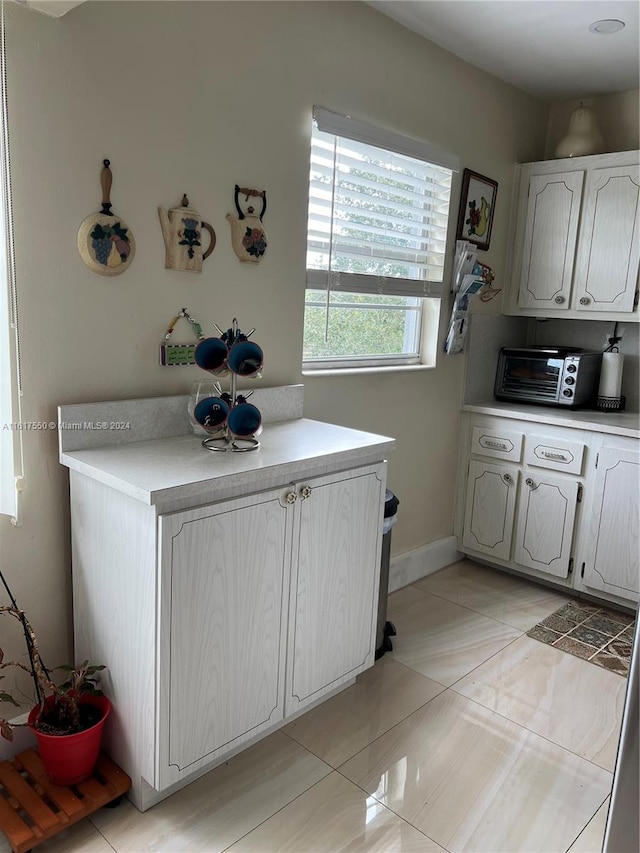 kitchen featuring light tile patterned flooring and white cabinetry