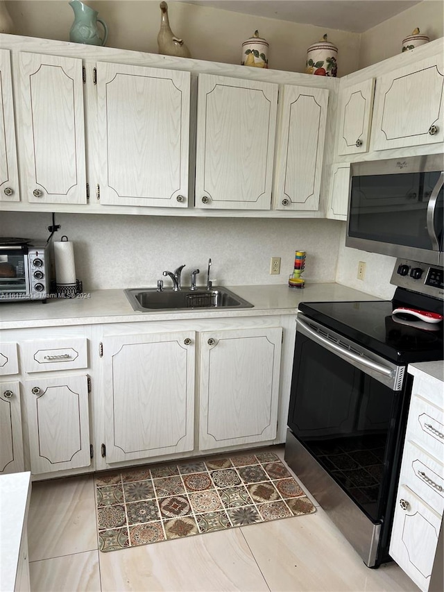 kitchen featuring sink, light tile patterned flooring, white cabinets, and stainless steel appliances