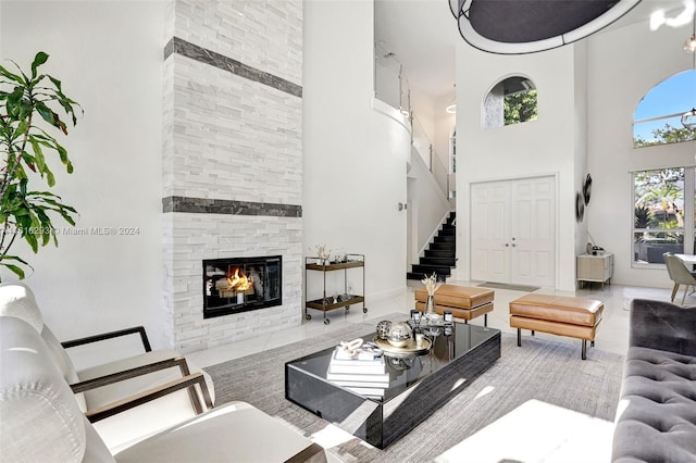 living area with stairway, a fireplace, and a towering ceiling