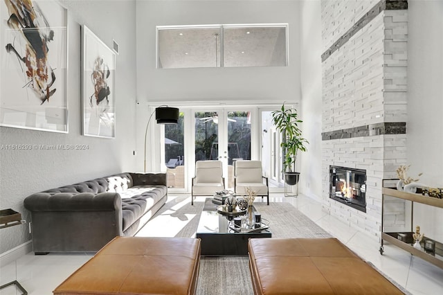 living room featuring a large fireplace, french doors, a high ceiling, brick wall, and tile patterned flooring