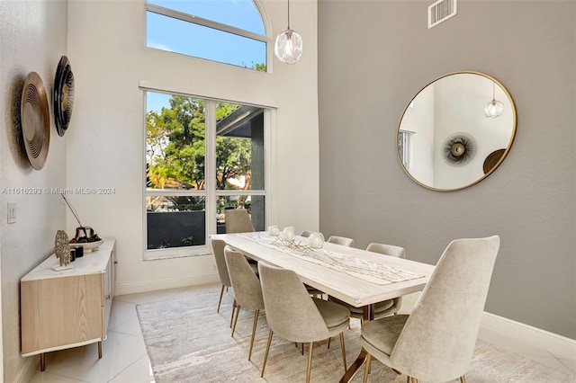 dining space featuring a towering ceiling and light tile patterned floors